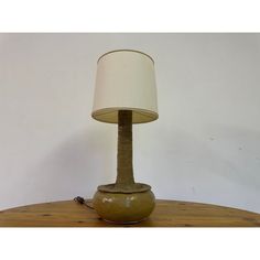 a lamp that is sitting on top of a wooden table next to a white wall