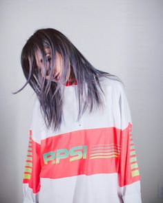 a woman with long hair wearing an orange and white shirt