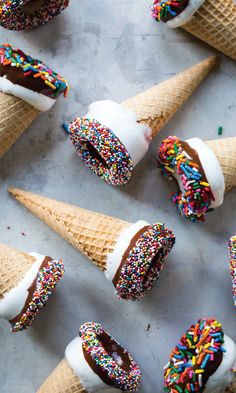 six ice cream cones with sprinkles and chocolate frosting in them on a table