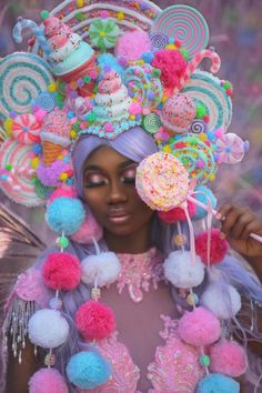 a woman with purple hair wearing a colorful hat and holding lollipops in front of her face