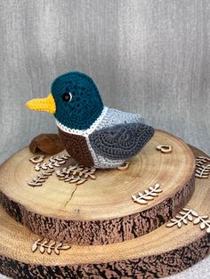 a crocheted bird sitting on top of a piece of wood