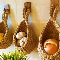 three baskets are hanging on the wall next to a potted plant and an orange