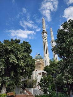 a large white building with two towers on it's sides and trees in the foreground