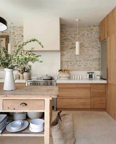 a kitchen with wooden cabinets and white dishes on the island in front of an oven