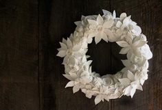 a white paper flower wreath hanging on a wooden wall