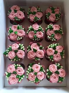 cupcakes with pink frosting and green leaves in a box