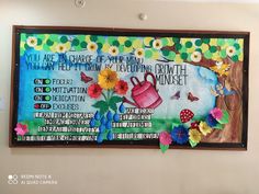 a bulletin board with flowers and watering can on the wall in front of a sign that says, you are an orange of what is your heart