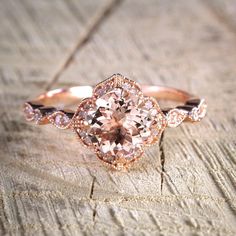 a pink diamond ring sitting on top of a piece of wood with diamonds around it