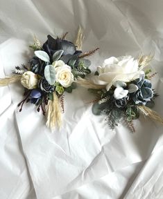 two white and blue flowers are laying on the sheeted surface, with one flower in the center