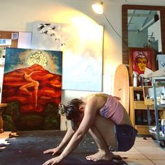 a woman is doing yoga in front of paintings