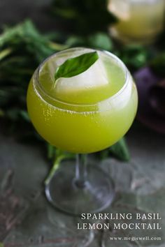 a close up of a drink in a glass with a green leaf on the rim