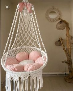 a white hanging chair with pink pillows