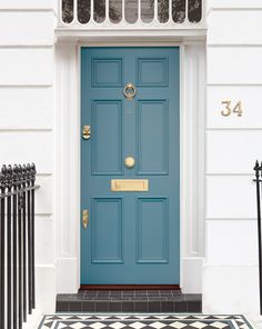 a blue front door with black and white tile on the ground next to a fence