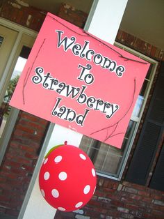 a welcome sign hanging from the side of a building with polka dot balloons attached to it