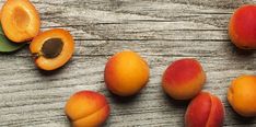 several pieces of apricot sitting on top of a wooden table next to leaves