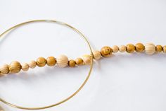 a wooden bead necklace is hanging on a hoop with a gold ring around it