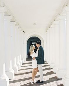 a man and woman are standing in an archway with columns on either side of them