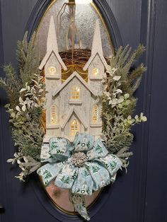 a christmas wreath is hanging on the front door with a lit up house in the background