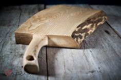 a wooden cutting board sitting on top of a wooden floor next to a knife holder