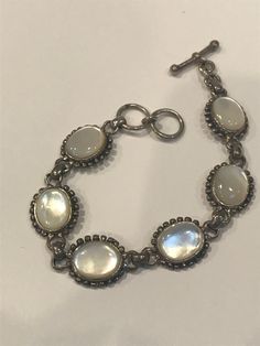 "Thiis is a beautiful, vintage, genuine, handmade Mother of Pearl and sterling silver bracelet that is adjustable and can be worn at either 7 inches or 7 1/2 inches. The bracelet is 5/8\" in width and features 6 Mother of Pearl links that measure about 3/4\" by 5/8\" each. The Mother of Pearls are set in polished sterling silver bezels with sterling silver beading around them. The MOP is so pretty, almost has the look of a Cat's Eye. The bracelet is stamped 925 and weighs about 22.1 grams. Gorgeous bracelet that is perfect for a bride to be or for wedding jewelry. See pictures for details.here Please note: This listing is for the bracelet only. The earrings and pendant seen in the last photo are being sold separately in my shop here: EARRINGS https://etsy.me/3CqwCwj PENDANT https://etsy.me Vintage Sterling Silver Bracelet Stamped 925, Antique Sterling Silver Adjustable Bracelet, Handmade Oval Sterling Silver Bracelet In Vintage Style, Adjustable Sterling Silver Bohemian Bracelet, Adjustable Vintage Bracelets Stamped 925, Vintage Adjustable Sterling Silver Bracelet Stamped 925, Adjustable Vintage Stamped 925 Bracelets, Adjustable Vintage Sterling Silver Bracelet, Adjustable Vintage 925 Stamped Bracelets