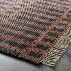 a brown and black rug with fringes on the bottom, sitting on top of a floor