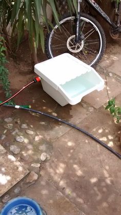 a bicycle parked next to a white cooler on the side of a road with a hose connected to it