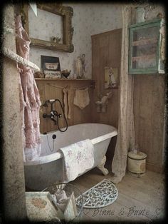 an old fashioned bathtub in a rustic bathroom with pink shower curtains and rugs