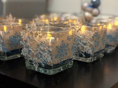 some glass candles are on a table with snowflakes and lights in the middle