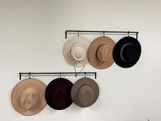 four hats are hanging on the wall and one has a hat rack attached to it