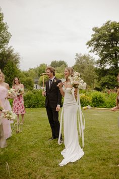 a bride and groom walking down the aisle at their outdoor wedding ceremony with guests in the background