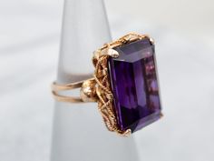 an amethyst purple stone ring sitting on top of a white stand