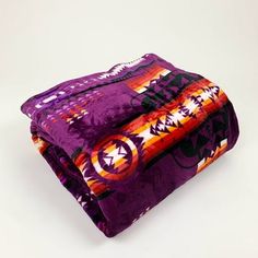 two purple and orange blankets sitting on top of each other in front of a white background