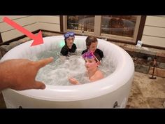 three children are in the hot tub and one is pointing at someone's hand