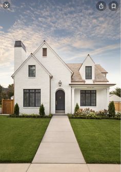 a white house with black shutters on the front door and windows in the middle