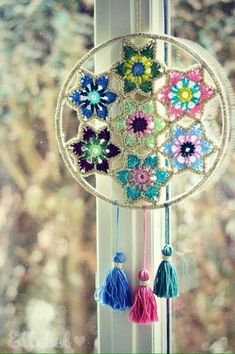 a window sill decorated with crochet flowers and tassels hanging from it