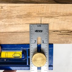 a person holding a ruler with a penny in front of it and measuring the width