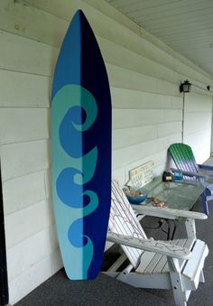 a blue surfboard leaning up against a white wall next to a table and chairs