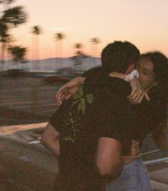 two people hugging each other in front of a car