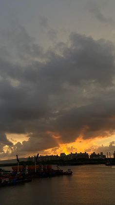 the sun is setting over some boats in the water and buildings on the other side