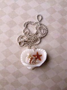 a starfish in a shell on a chain with a bead necklace attached to it