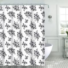 a shower curtain with black and white flowers on it in a bathroom next to a bathtub