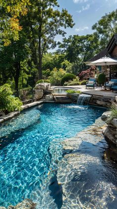 an outdoor swimming pool with blue water and rocks in the middle, surrounded by trees