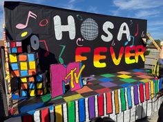 a group of people standing next to a colorful piano with musical notes on it's side