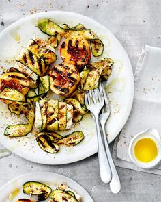 grilled chicken and zucchini on a white plate next to a cup of olive oil