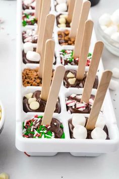 several trays filled with different types of candy and marshmallows on sticks