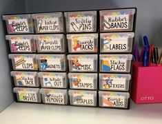 several plastic containers with labels on them are stacked next to a pink container filled with markers and pencils