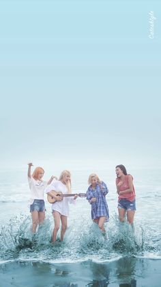 four girls are playing in the water with an acoustic guitar and one girl is singing