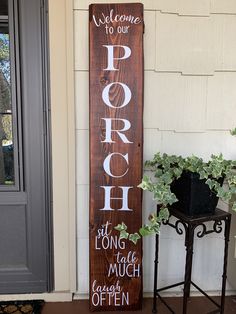 a wooden sign that says porch sitting next to a potted plant on the side of a house