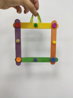 a child's hand holding a colorful wooden frame