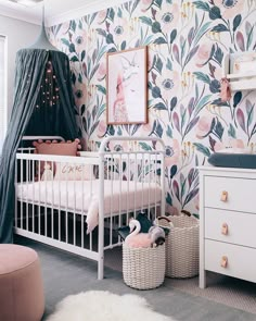 a baby's room with floral wallpaper and white furniture, including a crib